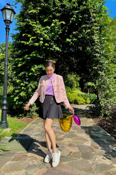 a lady in a purple top, a pink tweed jacket and a grey pleated skirt